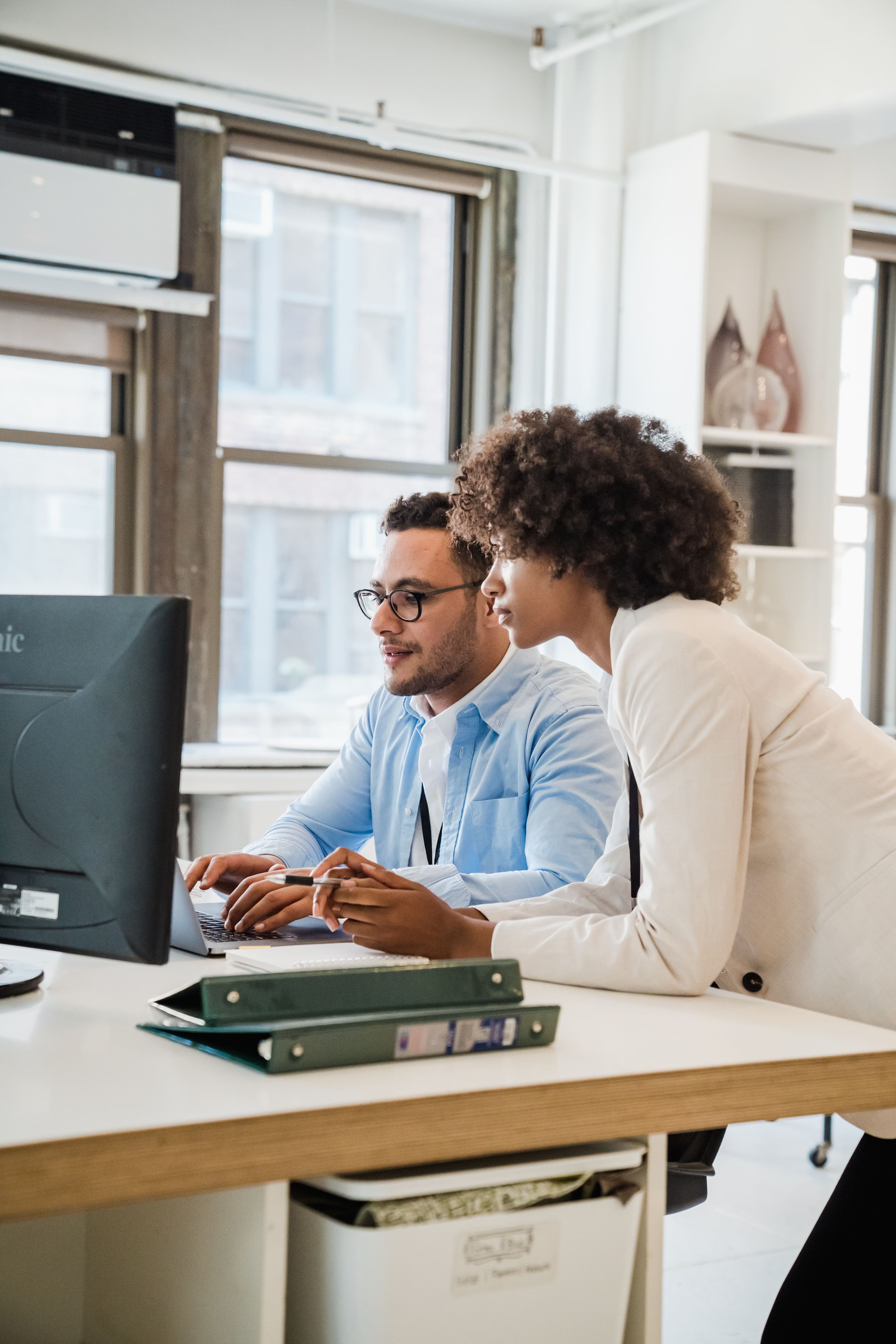 Two colleagues reviewing figures on a screen